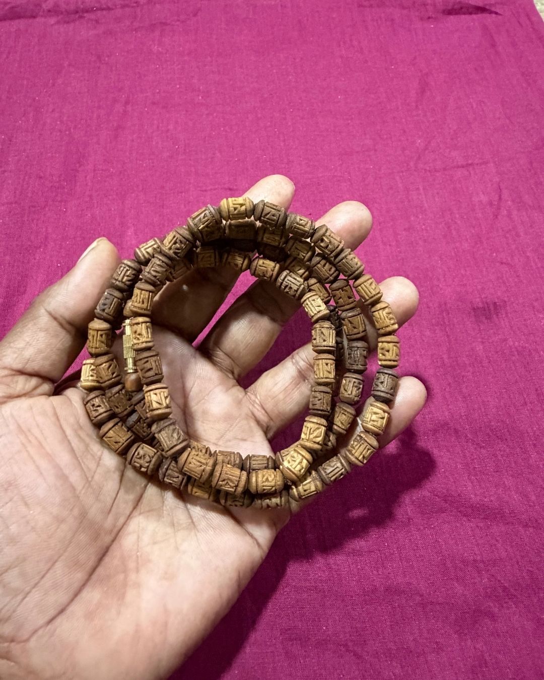 2 round brown radha name beads tulsi mala highlighting the brown Tulsi beads and Radha name design